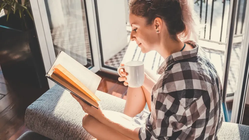 woman reading book with cup of coffee.